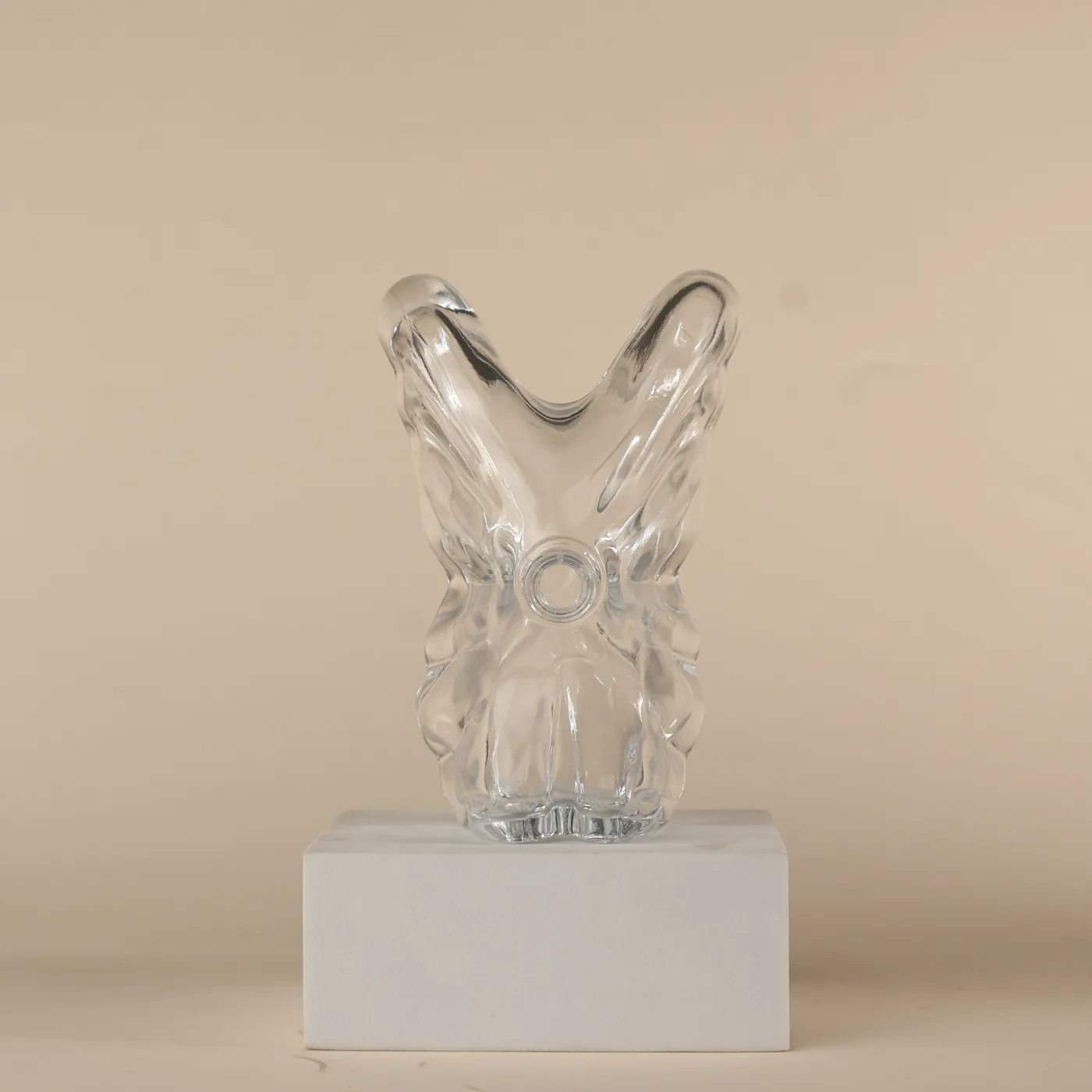 Clear sculptural perfume bottle on a display block